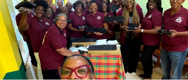 NY Chapter alumni in maroon shirts gathered with donated computer equipment